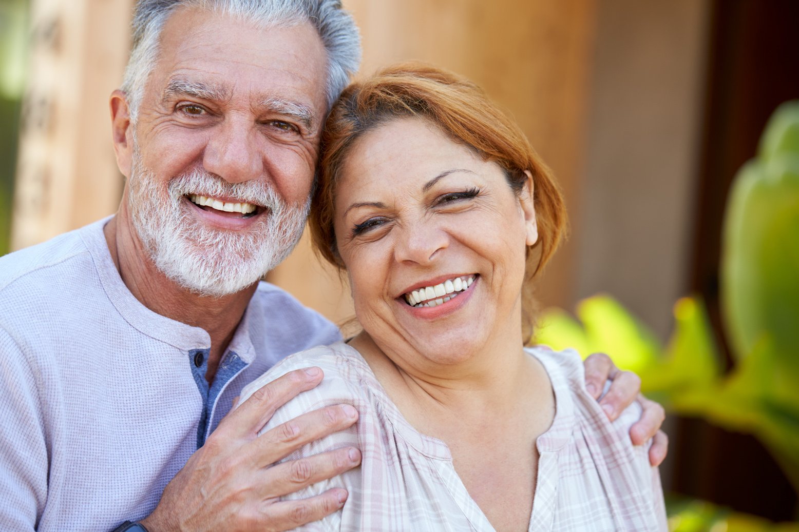 Portrait of Smiling Senior Hispanic Couple Relaxing in Garden at